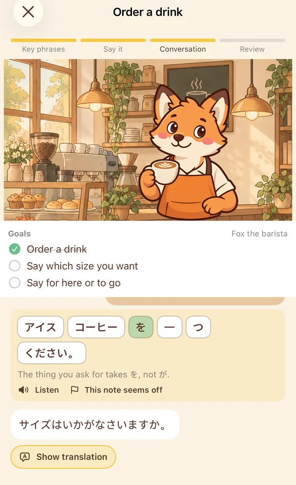 Conversation screen: the café scene with the fox barista. The player's sentence is shown as blocks with one particle replaced, above the note “The thing you ask for takes を, not が.” The barista then asks about the size.