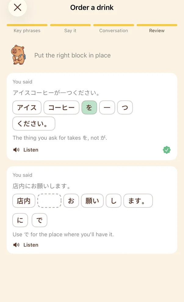 Review screen: the first sentence already has the right block in place. The second has a gap, with two blocks to choose from, に and で.